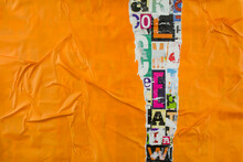 Torn And Crumpled Orange Paper On Colorful Collage From Clippings With Letters And Numbers Texture Background.