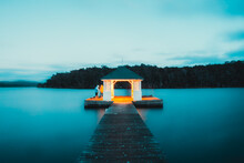 Twilight, Blue Hour Long Exposure Of A Small Hut At The End Of A Jetty, Blue Lake With Smooth Water