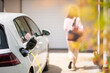 canvas print picture - Close up of a electric car charger with female silhouette in the background