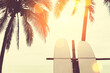 Surfboard and palm tree on beach background.