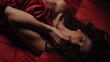 © stockbusters - Sexductive woman touching sexy lips. Attractive girl lying under red silk sheet
