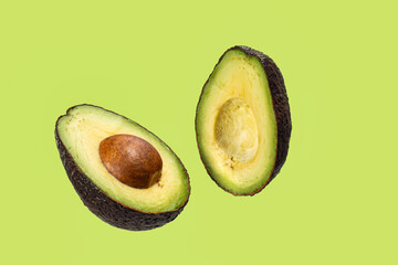 Avocado cutted in half with a motion effect on a green background.