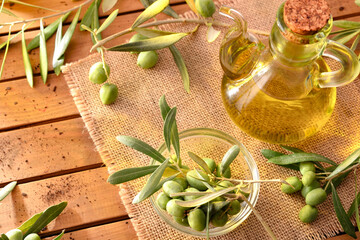 Wall Mural - Olive oil on table with branches and olives elevated view