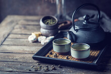 Still-life Of Japanese Healthy Green Tea In A Small Cups And Teapot Over Dark Background
