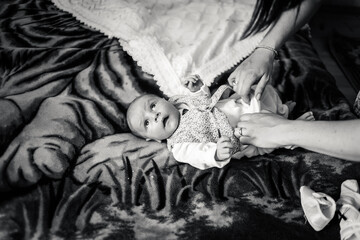  Black and white photo baby boy on a bed. Mother  dresses newborn child in suit for christening