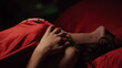 © stockbusters - Excited woman touching herself in bed. Hot lady lying under red silk sheet.