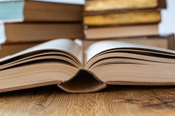 Open book with old books on a blurry background on a wooden table with a white background