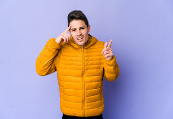 Young caucasian man isolated on purple background showing a disappointment gesture with forefinger.