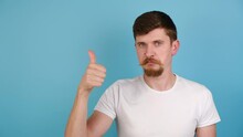 Young Man Showing Okay Hand Sign And Winking As If Approving Suggestion, Millennial Guy Completely Agree And Support, Dressed In White T-shirt, Isolated On Blue Studio Background With Copy Space