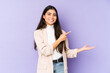 © Asier - Young indian woman isolated on purple background excited holding a copy space on palm.