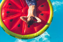 Boy chilling in pool on watermelon float