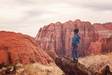 Little Boy By The Red Sandstone Cliffs And Mountains In Utah