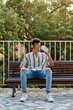 © Cavan Images - Young boy with afro hair drinks coffee while he is sitting on a bench