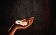 © Cavan Images - Hand reaching into a sparkling mist against a black background.