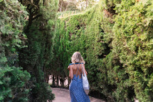 Woman Walking Through A Maze Of Bushes