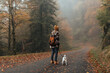 © JAVIER PARDINA/Stocksy - Portrait of a woman walking with her dog on the road in a misty cloud forest.