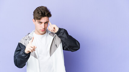 Wall Mural - Young caucasian man isolated on purple background pointing temple with finger, thinking, focused on a task.