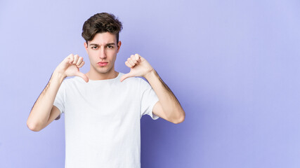 Wall Mural - Young caucasian man isolated on purple background showing a dislike gesture, thumbs down. Disagreement concept.