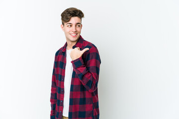 Wall Mural - Young caucasian man isolated on white background points with thumb finger away, laughing and carefree.