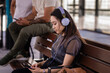 © Gillian Vann/Stocksy - woman listening to music waiting for the train