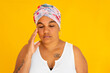 © Caro Telfer/Austockphoto - stressed woman with eyes closed and hand to face on yellow background