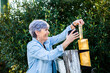 © Clare Seibel-Barnes/Austockphoto - Senior woman checking rain gauge on fence