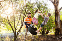 Dad Pushing Children On Tyre Swing Boy And Girl
