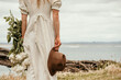 © Joanne O'Keefe/Austockphoto - Lady holds flowers and a hat by the sea.