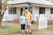 © Melissa Bernard/Austockphoto - Retired older couple husband and wife standing together in front of house happy smiling