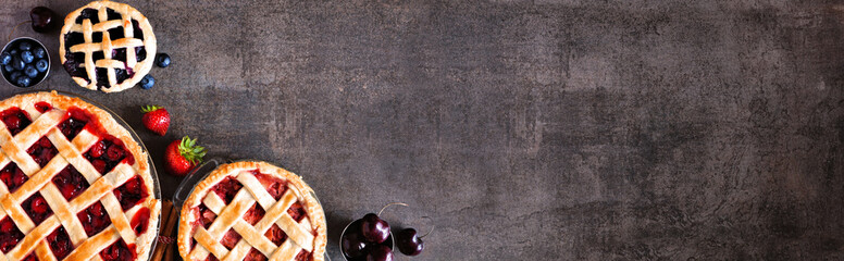 Poster - Selection of fresh fruit pies. Above view corner border over a dark stone background with copy space. Cherry, strawberry and blueberry.