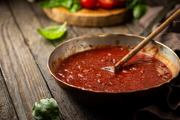 Wall Mural - Classic homemade Italian tomato sauce with basil for pasta and pizza in the pan on wooden background.