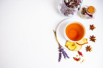 a white mug on a white table with herbal tea and herbal ingredients laid out on the table. Concept on the topic of herbal treatment for colds and flu in autumn. Top view