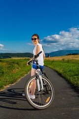 Wall Mural - Young woman riding a bicycle on country road
