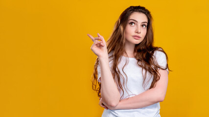 Curious woman portrait. Advertising background. Pensive lady pointing up at copy space isolated on orange. Sale discount. Special offer. Contact information. Opportunity chance.