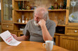 © Joe - Frustrated old man sitting and reading the eviction notice he just received..
