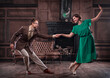 © karelian - a young couple dancing swing in a retro hall in front of a fireplace and a leathern sofa; the woman wears a green dress