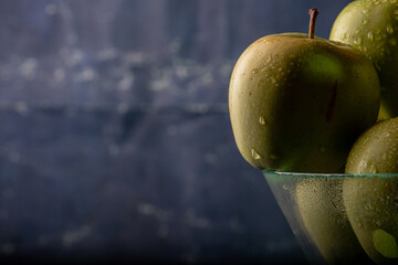 apples in a transparent vase on a blue background, one apple, three apples, fresh apples, red apple, green apple, yellow apple, bitten apple