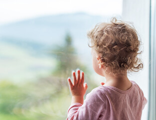 A lonely child looks out the window.