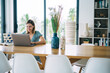 © BullRun - Smiling caucasian female digital nomad sitting at table in apartment satisfied with freelance job, happy clever 20s hipster girl learning online course and watching training webinar on laptop computer