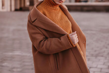 Young Woman  With Cropped Face In An Orange Knitted Sweater And Brown Coat Outdoor Portrait In Daylight. Cozy Autumn Fashion Style. 
