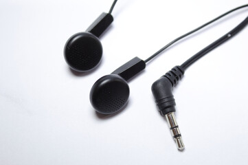 Black earphone with apparent wires and white background