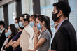 © nikomsolftwaer - Young people with face masks at work in office. Group of bussiness with face masks looking at camera, corona virus concept.