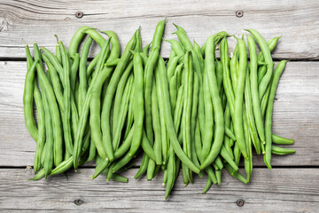 Many green bean pods on aged wood bench. Beautiful top view arrangement of  home grown blue lake pole bean harvest. Concept for self-sufficient gardening or healthy living or diet.