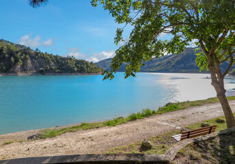 Lake of Castillion with blue melting water with surrounding forest mountains, commune of Saint-Julien-du-Verdon, Provence-Alpes-Côte d'Azur region, Alpes de Haute Provence, France