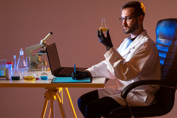 Poster - chemist on a brown background. a scientist with a flask in his hands is sitting at a table. a man ex