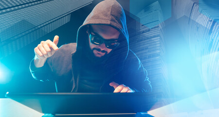 Poster - A bearded man with black glasses gestures next to a laptop. Working on a computer. Computer gadgets. Hacker. An emotional man is typing on a computer.