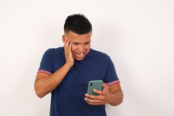 Close-up portrait of Young handsome hispanic man wearing casual t-shirt standing over white isolated background holding in hands cell reading sms using new app 5g