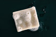 Soap bar natural diy olive oil foaming with foam bubbles texture on black background .Top view. Washing hands with soap for personal hygiene.