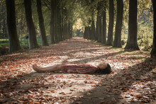 Teenage Girl In Dress Lying On Path In Forest
