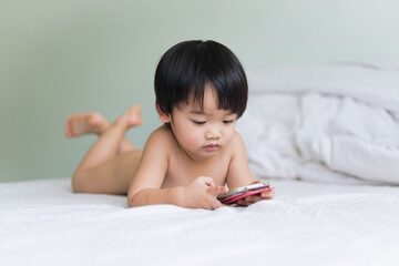 Little boy playing smartphone on the bed